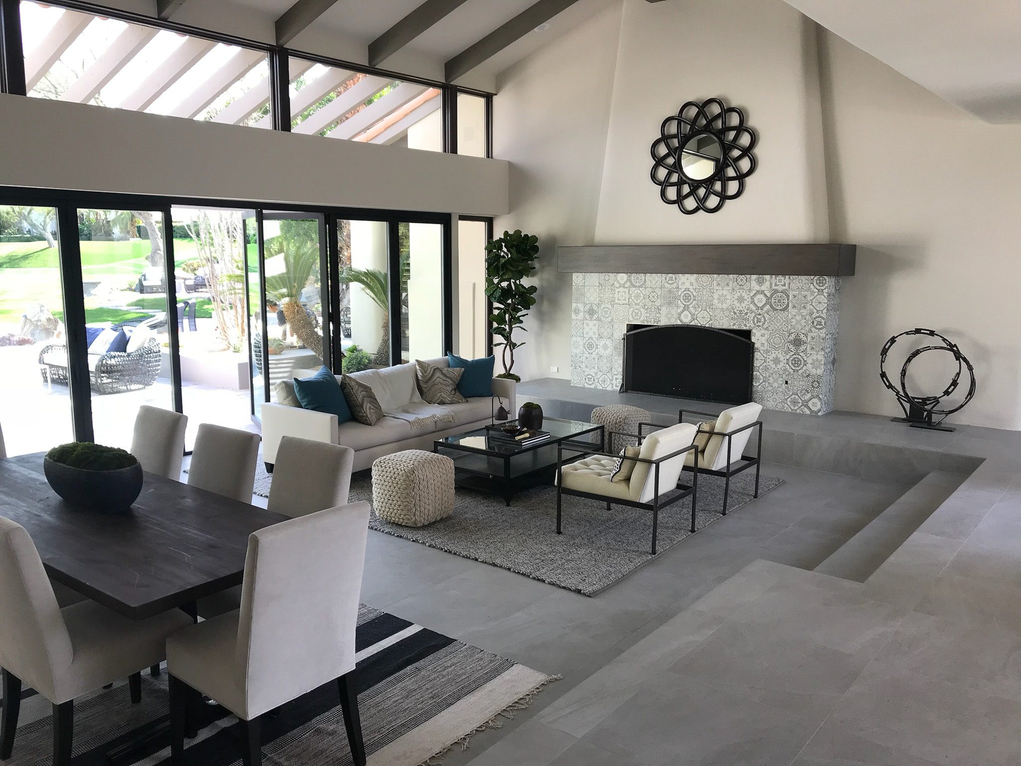 IMG_7154 Spacious living room with a modern design, featuring a fireplace, large sofas, and a dining area, overlooking a lush garden.